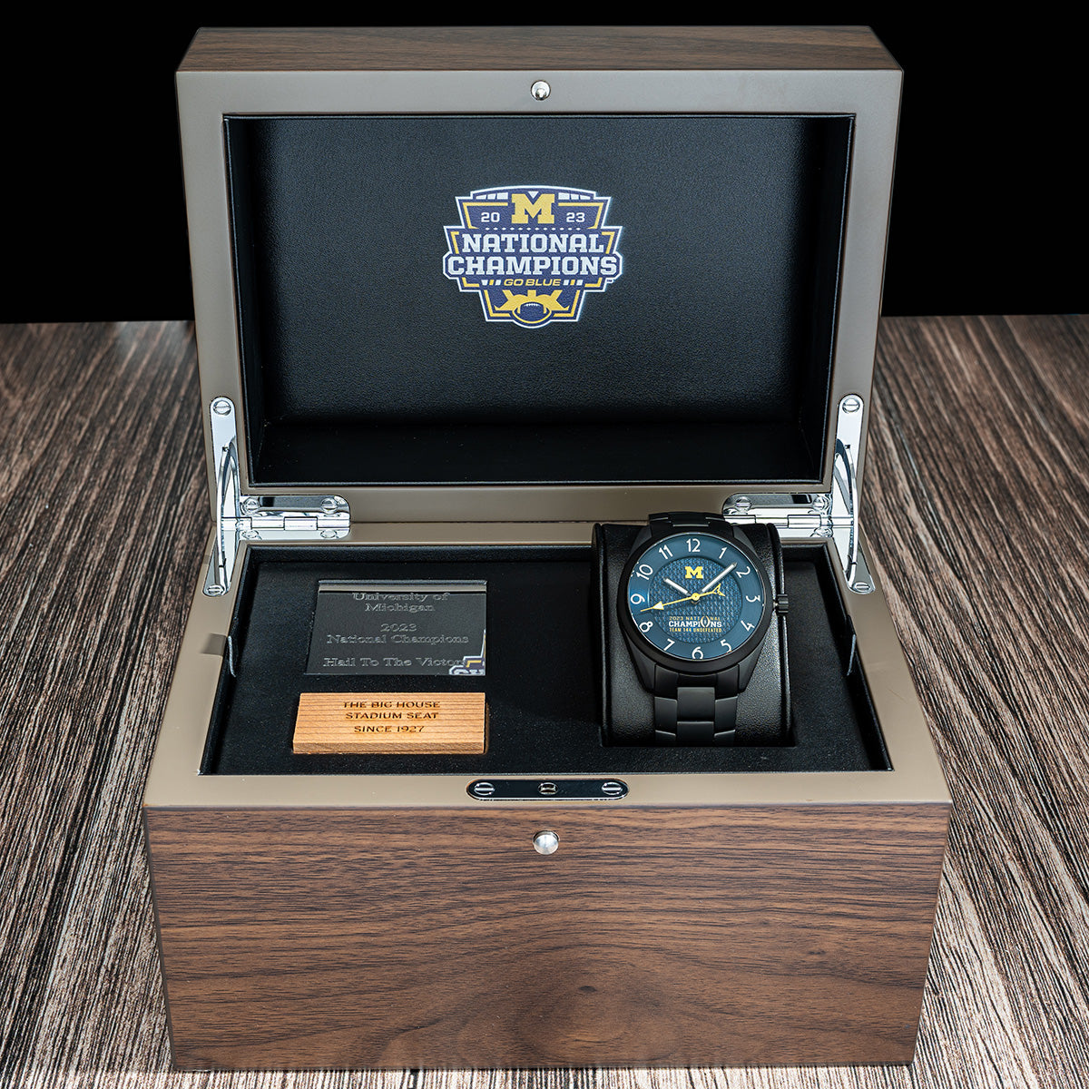 Wood display box featuring a piece of wood from a big house stadium seat originally installed in 1927 and the Michigan 2023 National Champions Black PVD Kairos II CFP 2024 swiss made automatic watch. Black PVD bracelet.