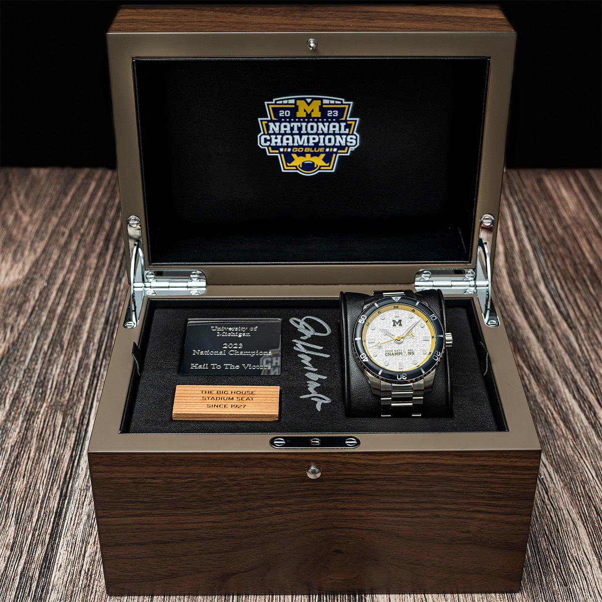 2023 Michigan National Champions Jim Harbaugh autographed display box with the Odysseus Swiss made automatic watch and a piece of wood from The Big House stadium seats originally installed in 1927.